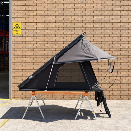 CZY AIR rooftop tent side profile on the original ToughBuilt sawhorses and timber frame outside a clean brick warehouse.