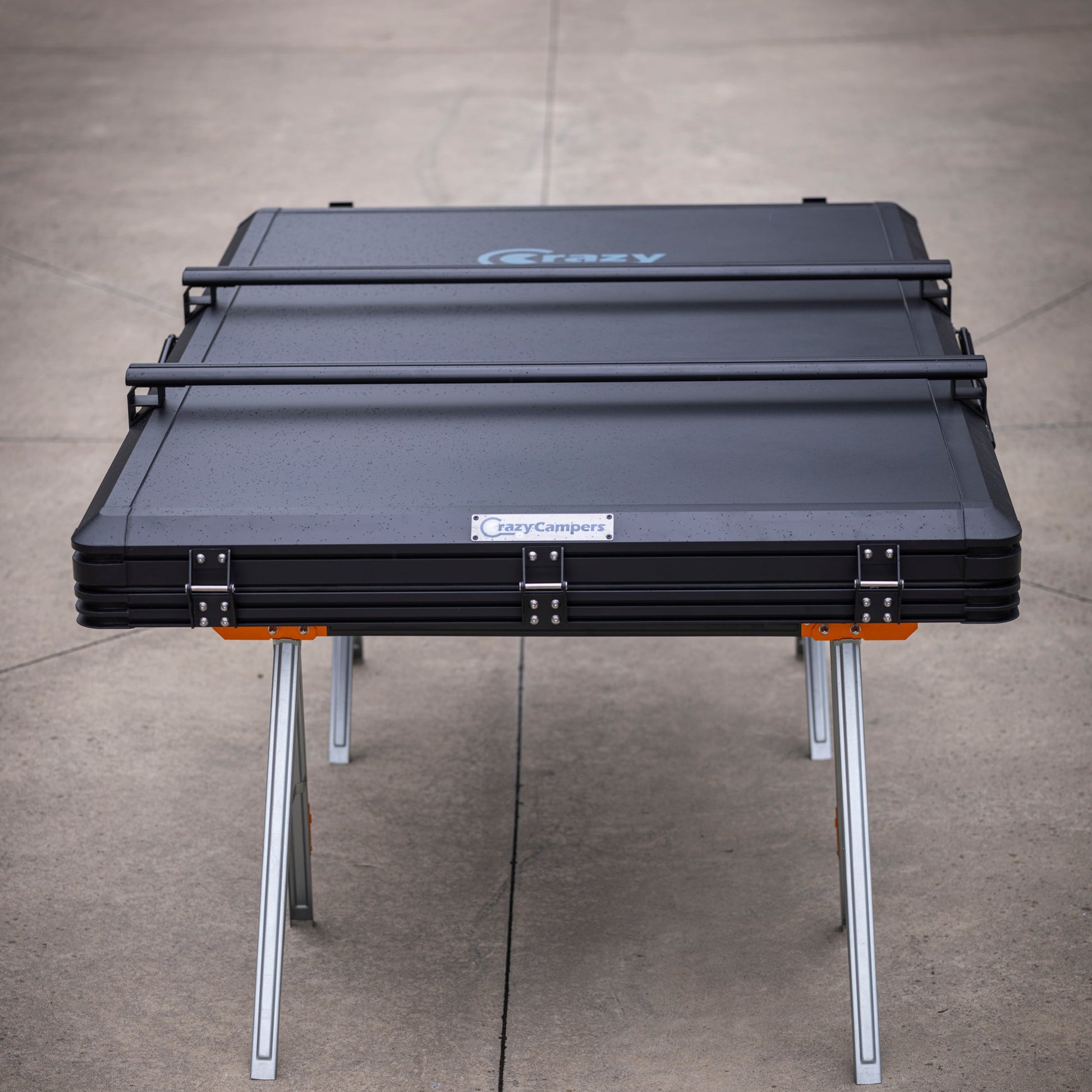 Black CrazyCampers TrailReady 1450 hard shell rooftop tent shown closed on display legs