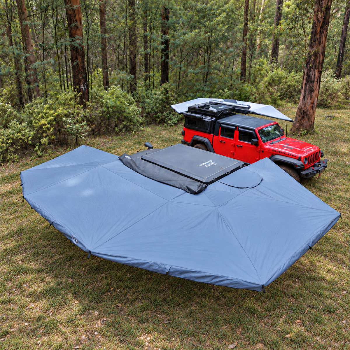 Oblique view of the XL 270 Plus awning deployed beside a grey ute on grass, with the rooftop tent closed.
