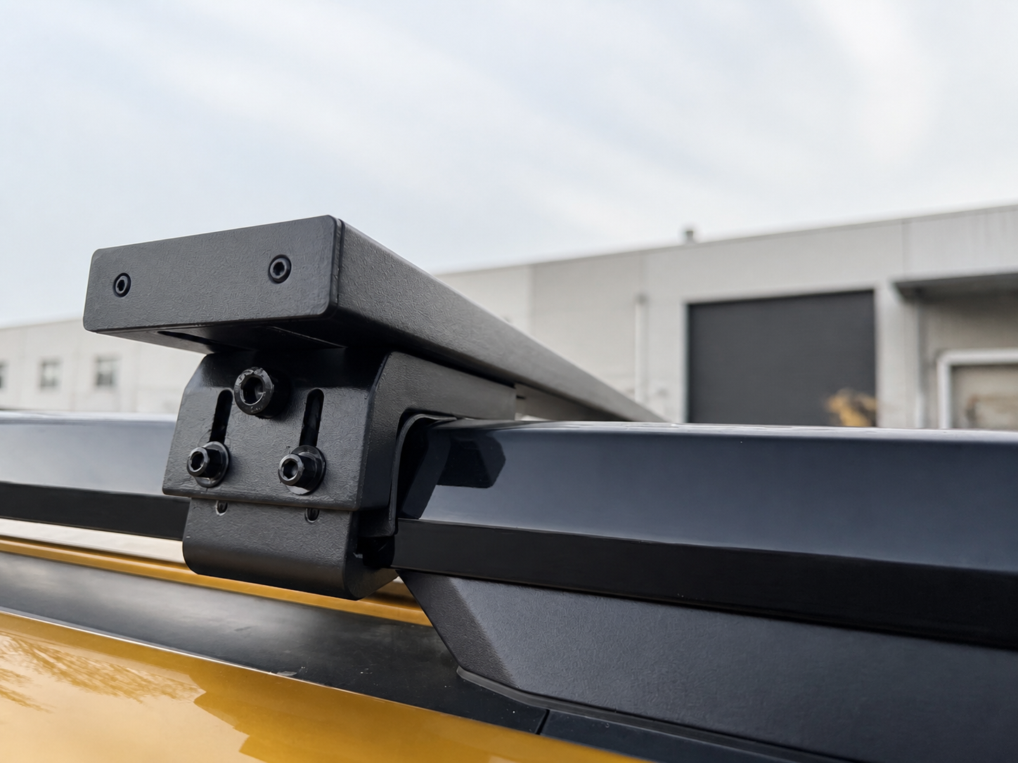 Close-up of a 1450 cross bar fitted to a raised vehicle roof rail